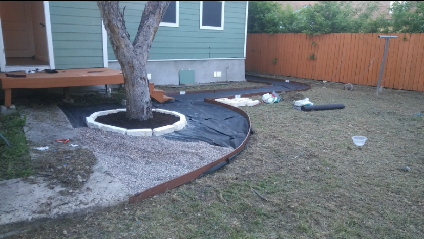 Curved landscape edging and fabric installed around a backyard tree