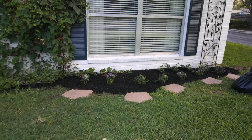Completed window flower bed with fresh mulch and stepping stones